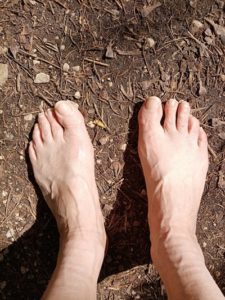 des pieds nus sur la terre avec brindille en guise de carte d'identité